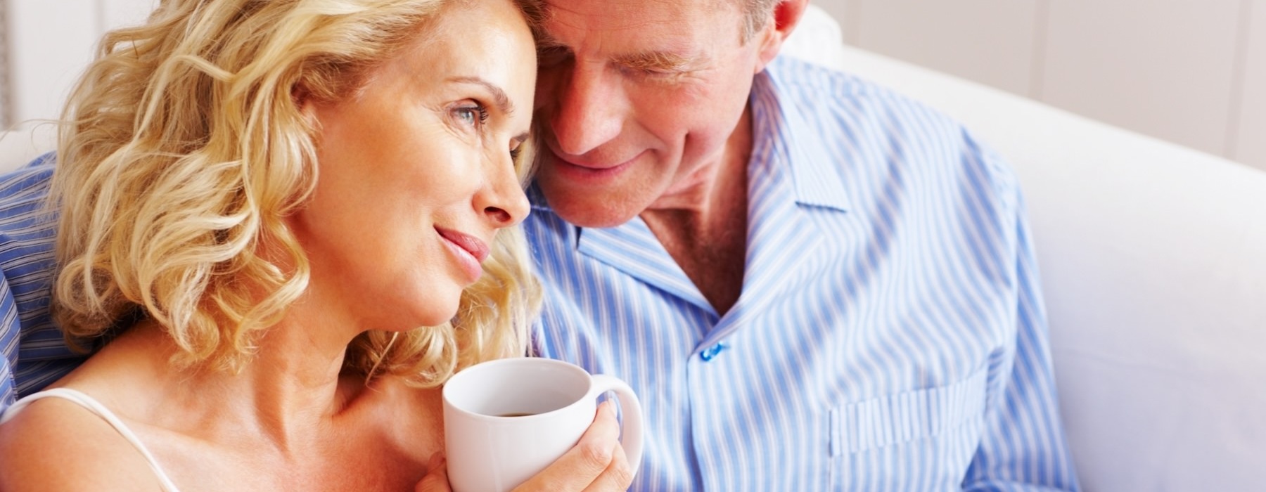 a man and a woman sitting on a couch holding coffee mugs