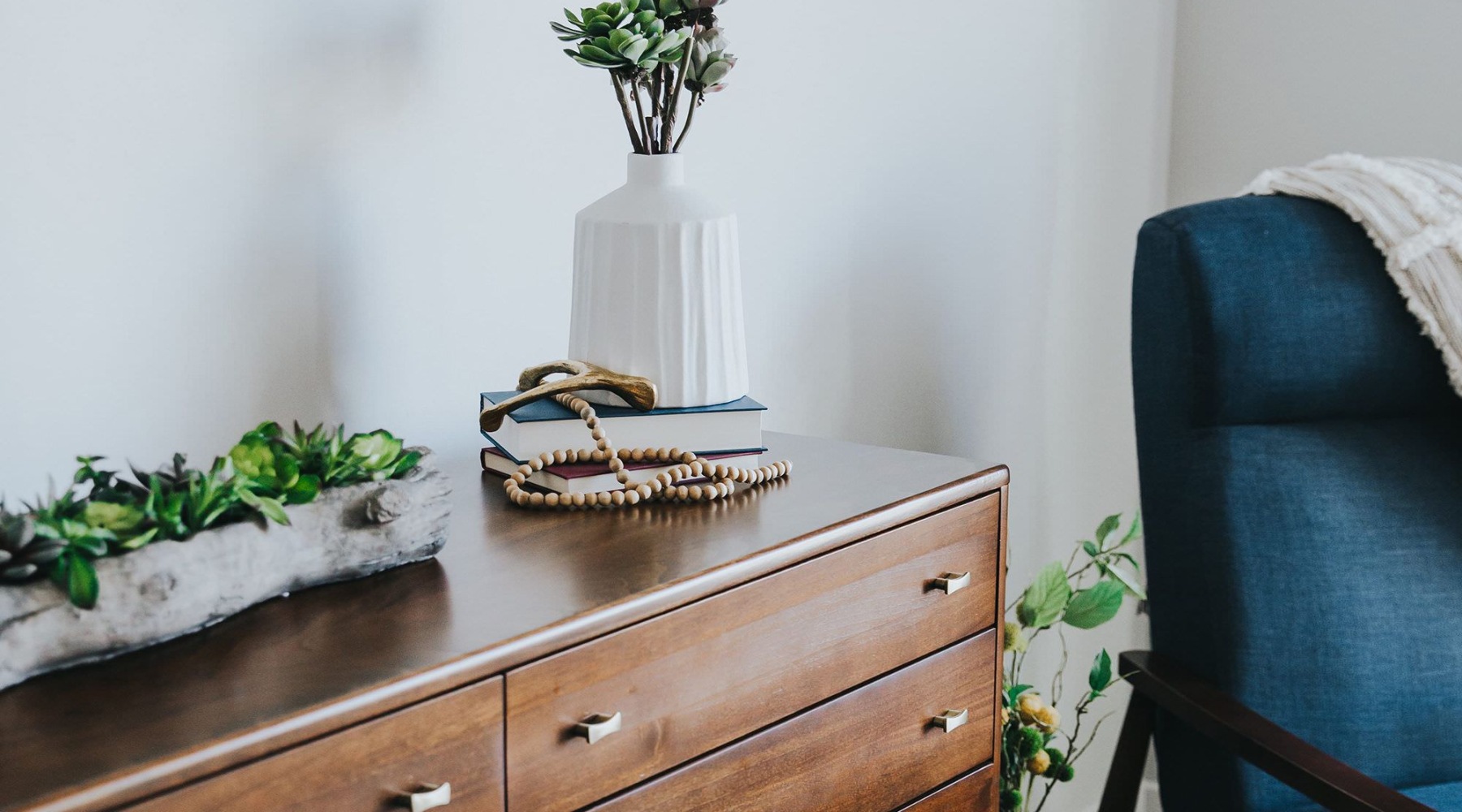 a dresser with a vase of plants on top